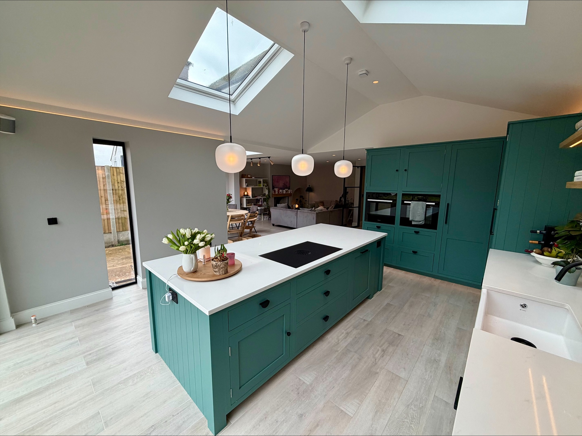 Open-plan kitchen with green shaker island and roof lights